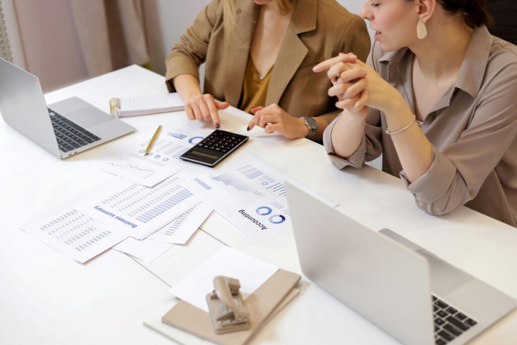 Two people reviewing printed reports at a desk, with a rubber stamp beside the papers
